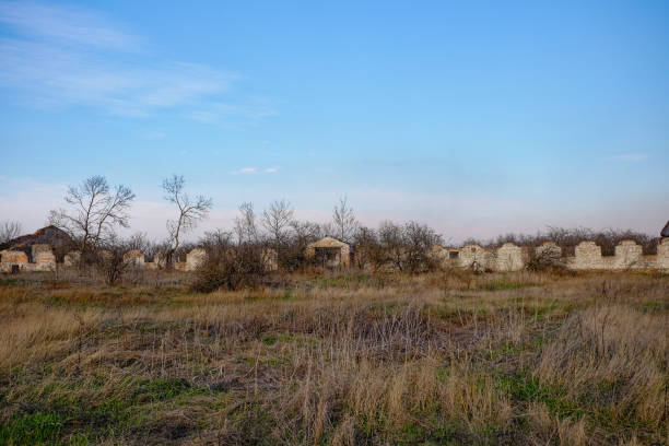A crumbling brick wall, remnants of a larger structure, stands in an open field.