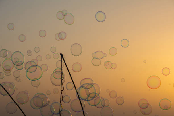 Lots of colorful soap bubbles floating in the orange sky at sunset with soap bubble stick