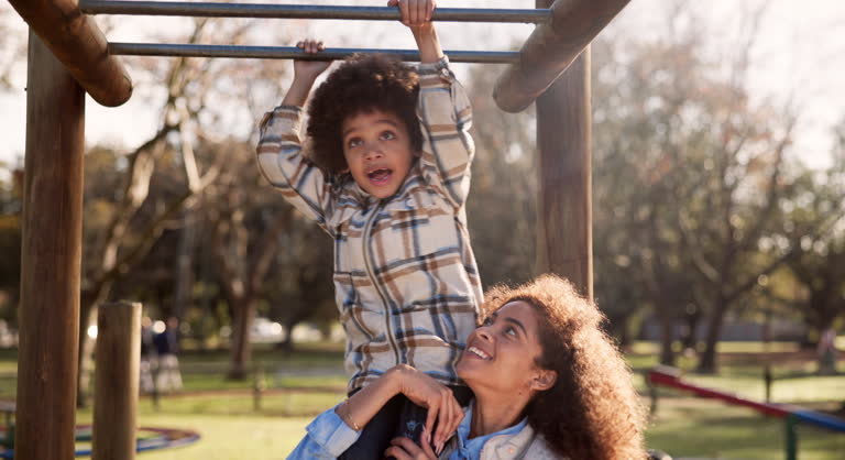 Mother, child and playing with monkey bars at park for fun bonding, outdoor holiday or weekend in nature. Happy little boy or kid with parent in joy or happiness for hanging in playground at forest