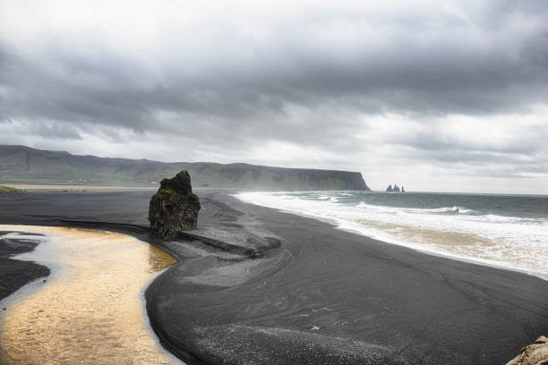 Vik, Iceland  black sand against the deep blue  The volcanic landscape adds a dramatic touch to this breathtaking picture,  The waves crashing against the shore evoke a sense of power and beauty, making it a truly unforgettable sight,Vik black sandy beach Iceland