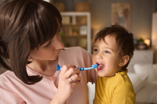 istock Mother teaching and helping her son brush his teeth at home 2155913089