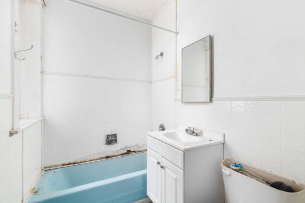 A bathroom with water damage and the walls falling apart.