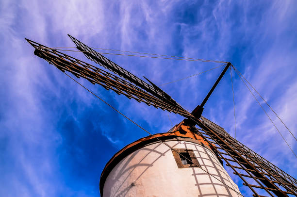 A windmill is standing tall in the sky with a blue sky behind it. The windmill is a symbol of the power of nature and the importance of renewable energy