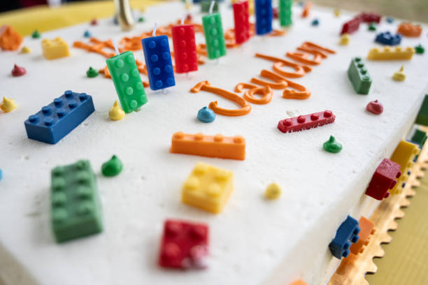 Birthday cake has white frosting and decorated with colorful building blocks as candles.