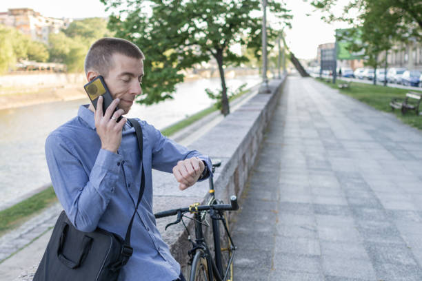 istock Smiling businessman commuter using mobile phone. He is enjoying at public park on his bicycle trip from work after a long workday. Sustainable concept of going to work by bicycle. 2155923594