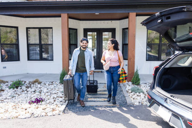 istock Husband wheels suitcases while wife carries tote bag 2155928085