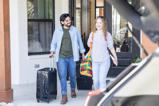 istock Husband looks at wife while taking suitcases out to car 2155928088