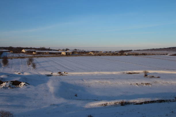 istock A snowy field with buildings and a blue sky 2155928884