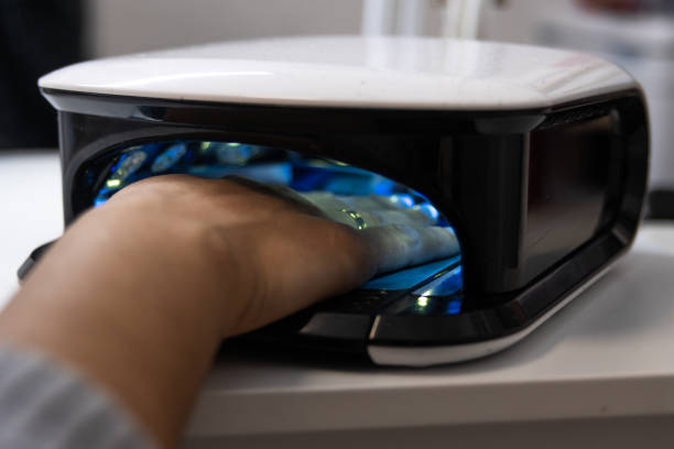 istock Client's hand in a UV nail dryer at salon 2155938746