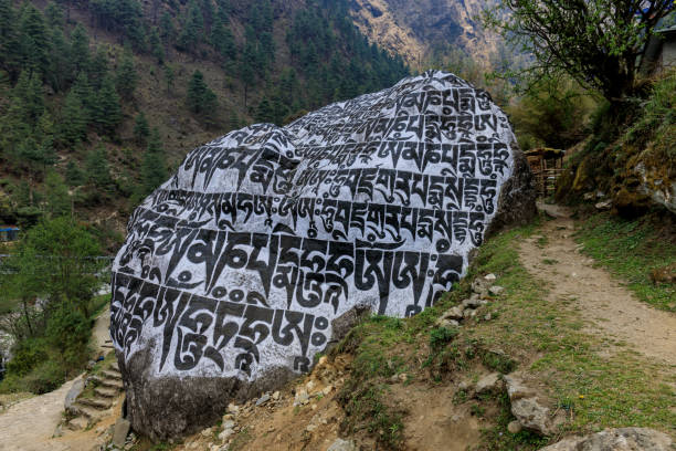 Nepal sacred stones mani with mantra written and carved on the surface. Prayer stones shire on the mountain trekking path on Everest Base Camp trek. Nepali buddhist mantra Om Mani Padme Hum on rock