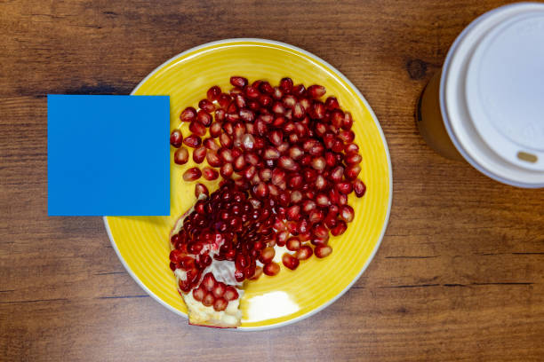 High-angle view of an blue sticky note placed on a yellow plate with a pomegranate on it