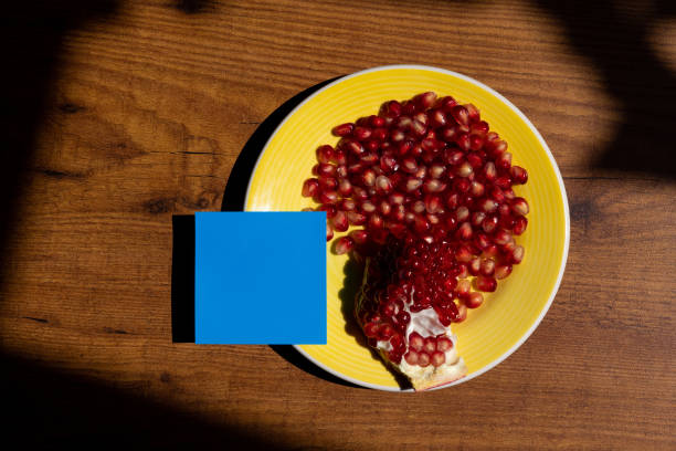 High-angle view of an blue sticky note placed on a yellow plate with a pomegranate on it