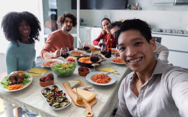istock Happy multiracial man taking selfie with friends while sitting together at dining table during lunch 2155954448