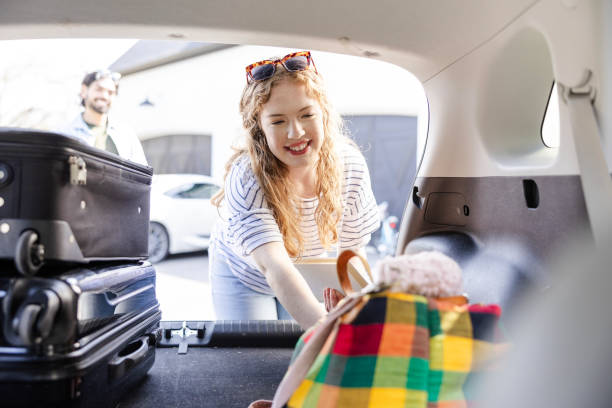 istock Husband waits while wife finishes loading items in trunk 2155954740