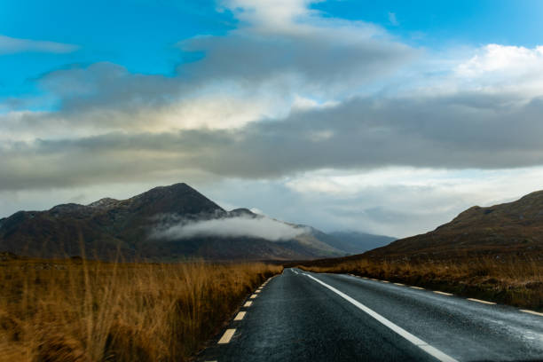 Wet road going in to the mountains in a cloudy day