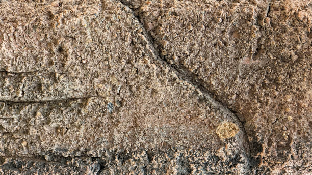 istock A rough, weathered stone wall with a few small cracks 2155960200