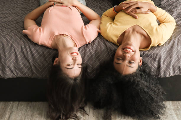 istock Two multiracial girls share a joyful moment lying upside down on a bed, exuding happiness and relaxation, illustrating carefree companionship and the joy found in spending leisure time with friends 2155961861