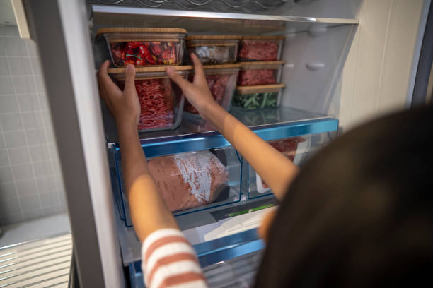 A little girl arranges a snack container on the refrigerator