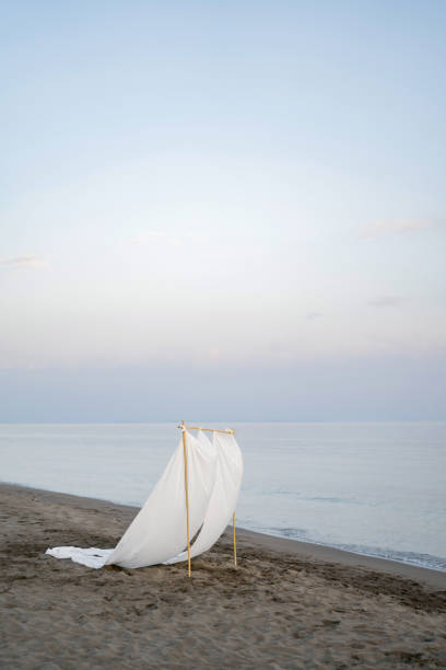 istock Wedding arch with fluttering white sheets stands on a sandy beach by the sea 2155968464