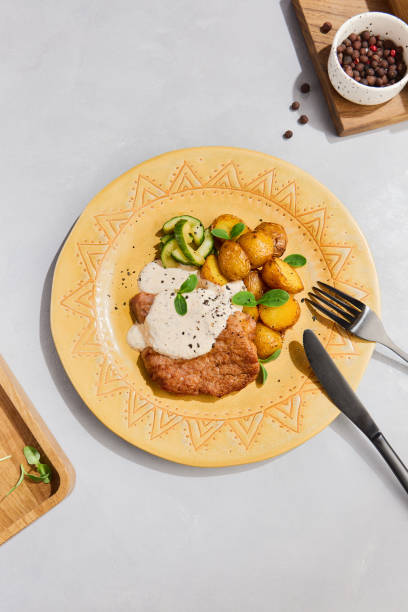 istock Pork Chop with Potato Wedges and Sauce on a Decorative Plate 2155971978