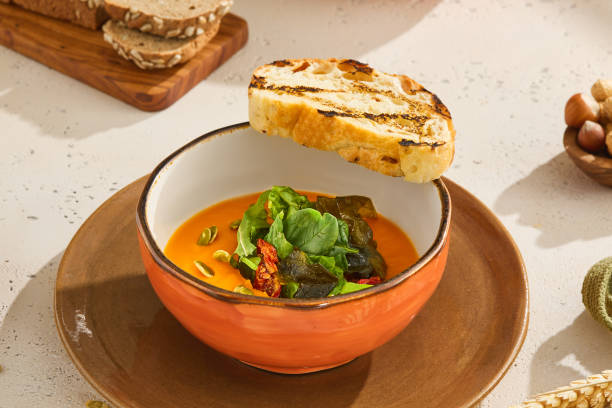 istock Delicious Pumpkin Cream Soup with Fresh Herb Mix and Toast in Rustic Setting 2155972134