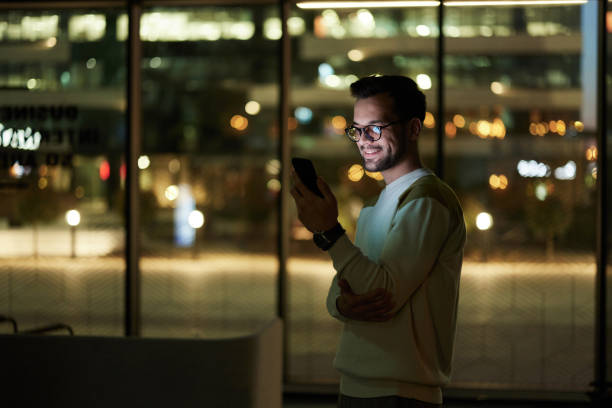 istock Happy man text messaging on cell phone indoors at night. 2155977600