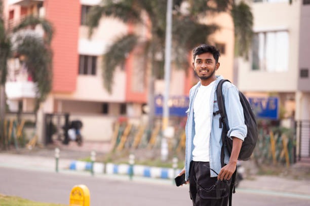 istock Cheerful student looking over shoulder while walking on sidewalk in the city 2155978355