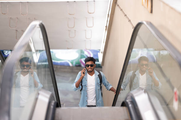 istock Young Man on Escalator Talking on Phone 2155978693