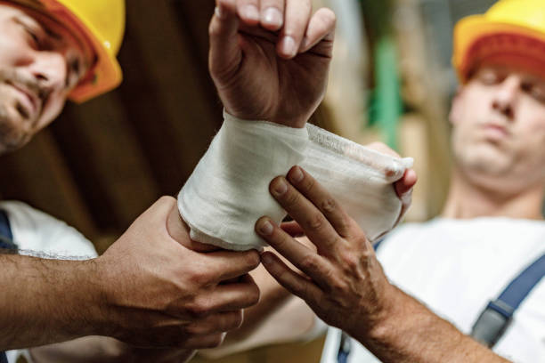 Close up of manual worker assisting his colleague with physical injury in a warehouse.