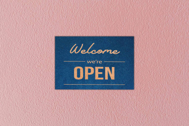 welcome we're open, Retro style with text on pink concrete wall.