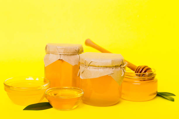 istock Honey in jar with leaves and honey dipper on colored background top view with copy text 2155980715