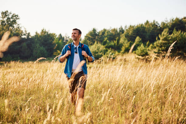 istock Adult man walking through countryside meadow with backpack 2155981451