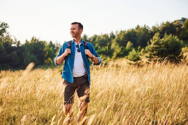 istock Mid adult man walking alone with backpack in countryside during summer weekend trip 2155981485