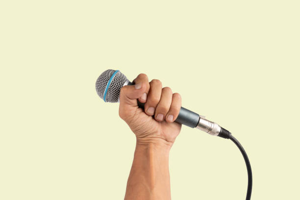 istock Black male hand holding a microphone isolated on green background 2155981629