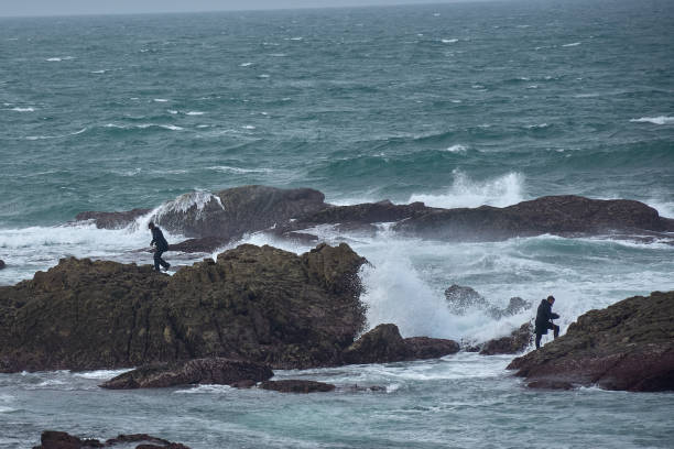 Baiona, Pontevedra, Spain; October 26, 2022: Fishermen among the rocks and waves, in the dangerous barnacle fishing.