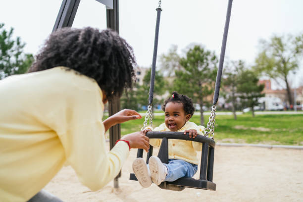 istock A woman is holding a baby on a swing 2155985477