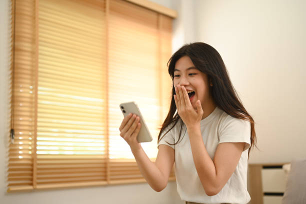 istock Shocked young asian lady looking at smartphone screen excited by unexpected notification 2155987760