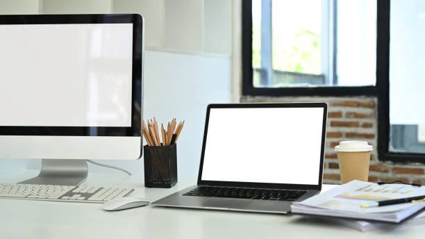 istock Blank computer monitor, laptop and financial document on white table in office 2155987950