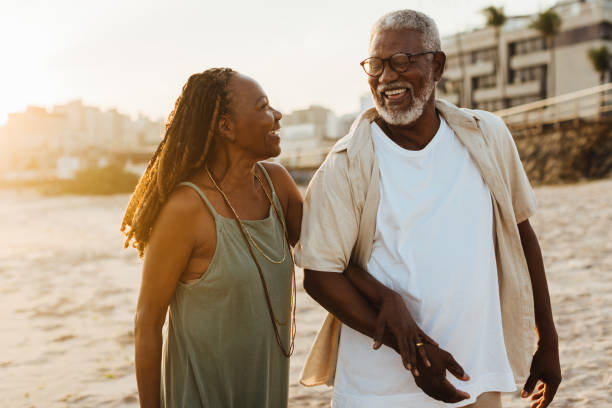 istock Elderly couple walking on the beach at sunset 2155990214