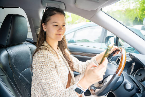 istock Young woman driving a car and using smartphone application to view a map showing travel route 2155991397
