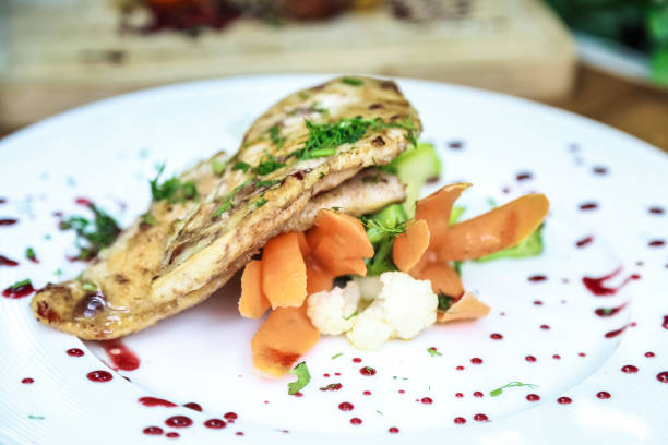 A white plate is filled with a delicious combination of moist meat and colorful, fresh vegetables.