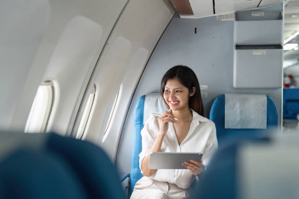 istock A woman is sitting on an airplane with a tablet in her lap 2155993589
