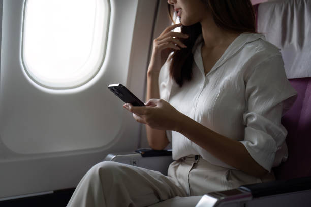 istock Asian business woman on aeroplane using smartphone 2155993969
