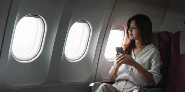 istock Asian business woman on aeroplane using smartphone 2155994057