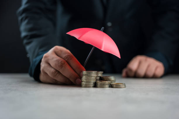 istock Businessman hand holding a red umbrella over stack of coins. Financial security and savings protection concept. 2155994548