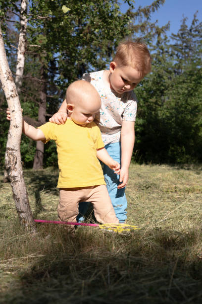 Two children experience joy and freedom as they stretch their arms wide while standing near a majestic tree in Sydney. The sun shines brightly, creating a joyful weekend atmosphere.