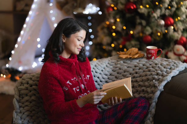 istock Relaxed woman reading a book during Christmas holidays 2155996339