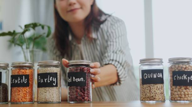 Close up woman  hand organizing glass jar containers with various dry goods such as red bean healthy eating,buying organic grains with reusable natural zero waste  eco friendly sustainable food packaging eco-friendly in sustainable Plastic Free grocery store