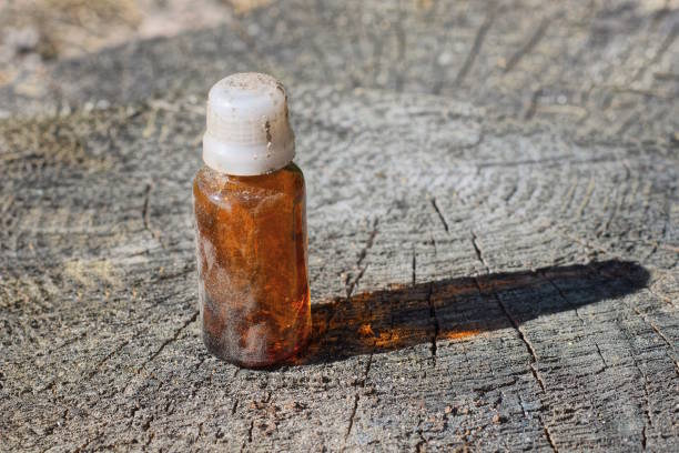 one old small brown white glass closed bottle stands on a gray wooden stump in the street