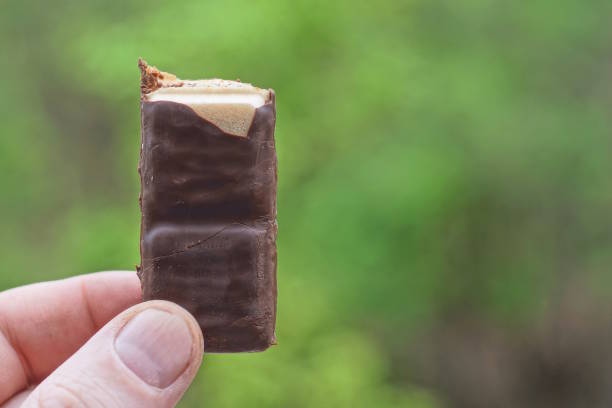 istock hand holding one brown chocolate bar outdoors 2156000595